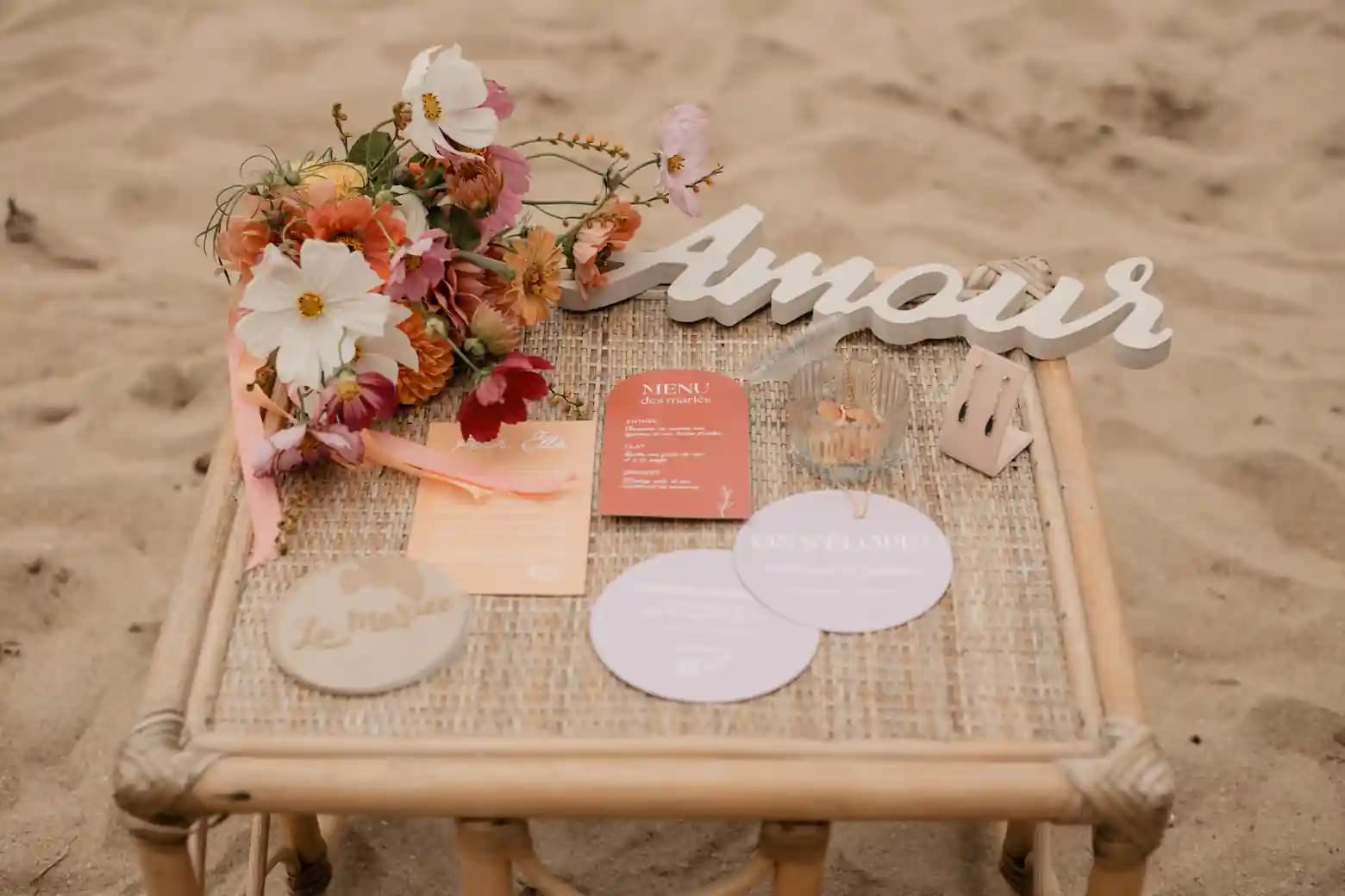 Papeterie de mariage sur mesure : menus des mariés et marque-places sur une table en rotin