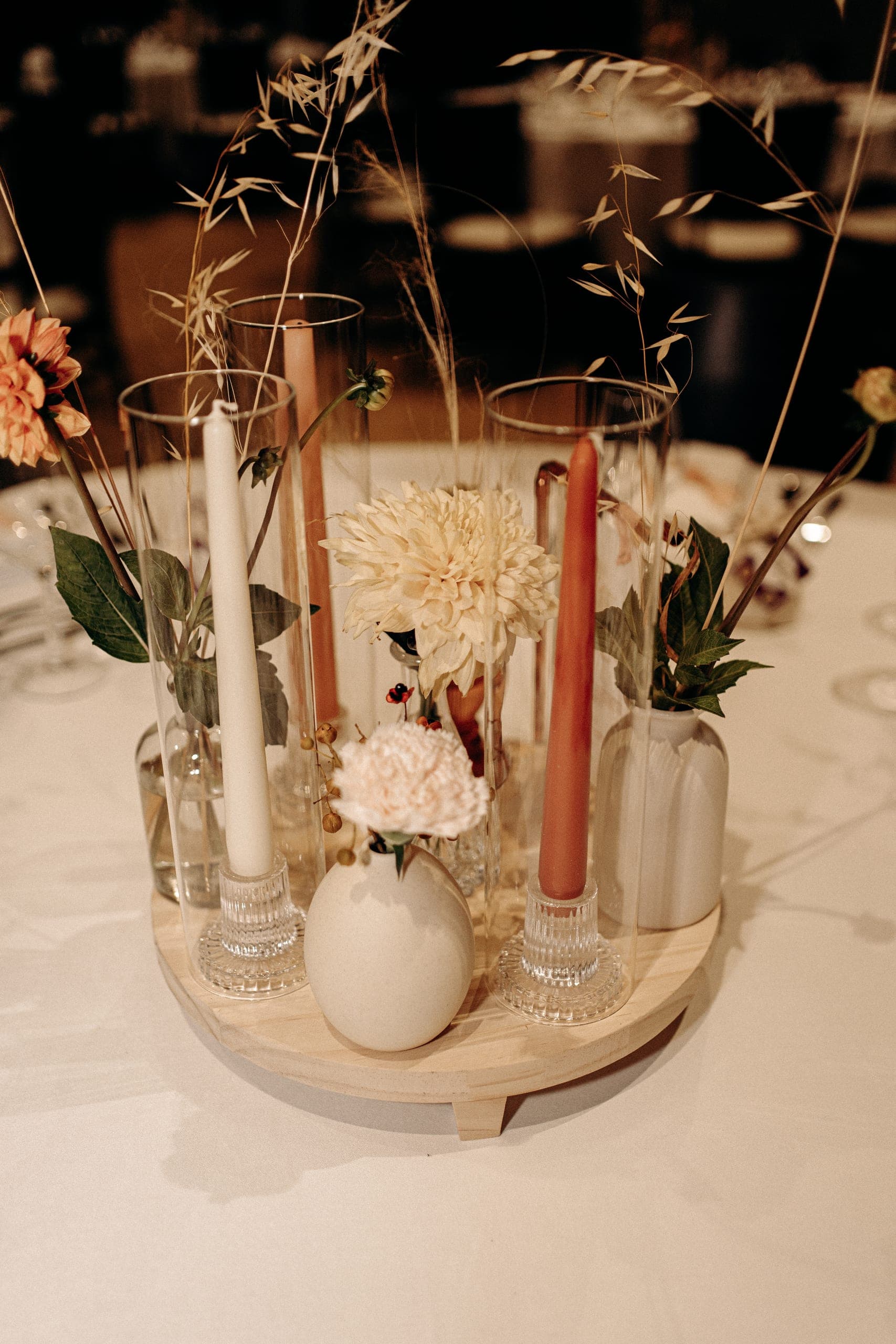 Centre de table bohème sur plateau en bois : vases dépareillés, bougies terracotta et dahlias