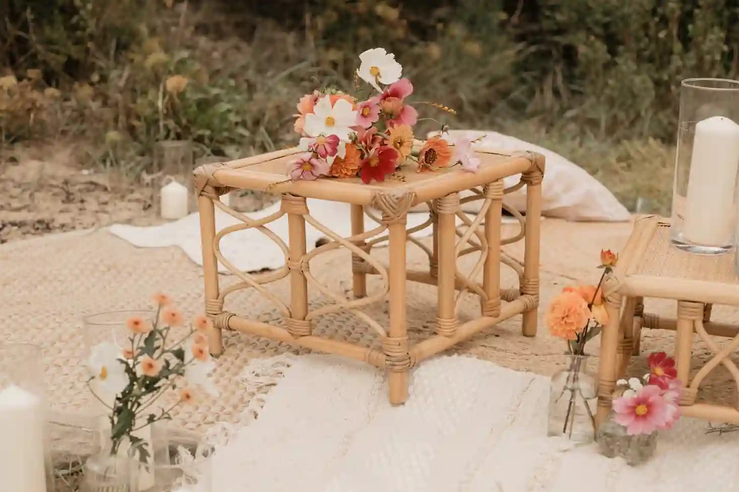 Espace lounge dans la dune : tables basses en rotin, coussins et bougies